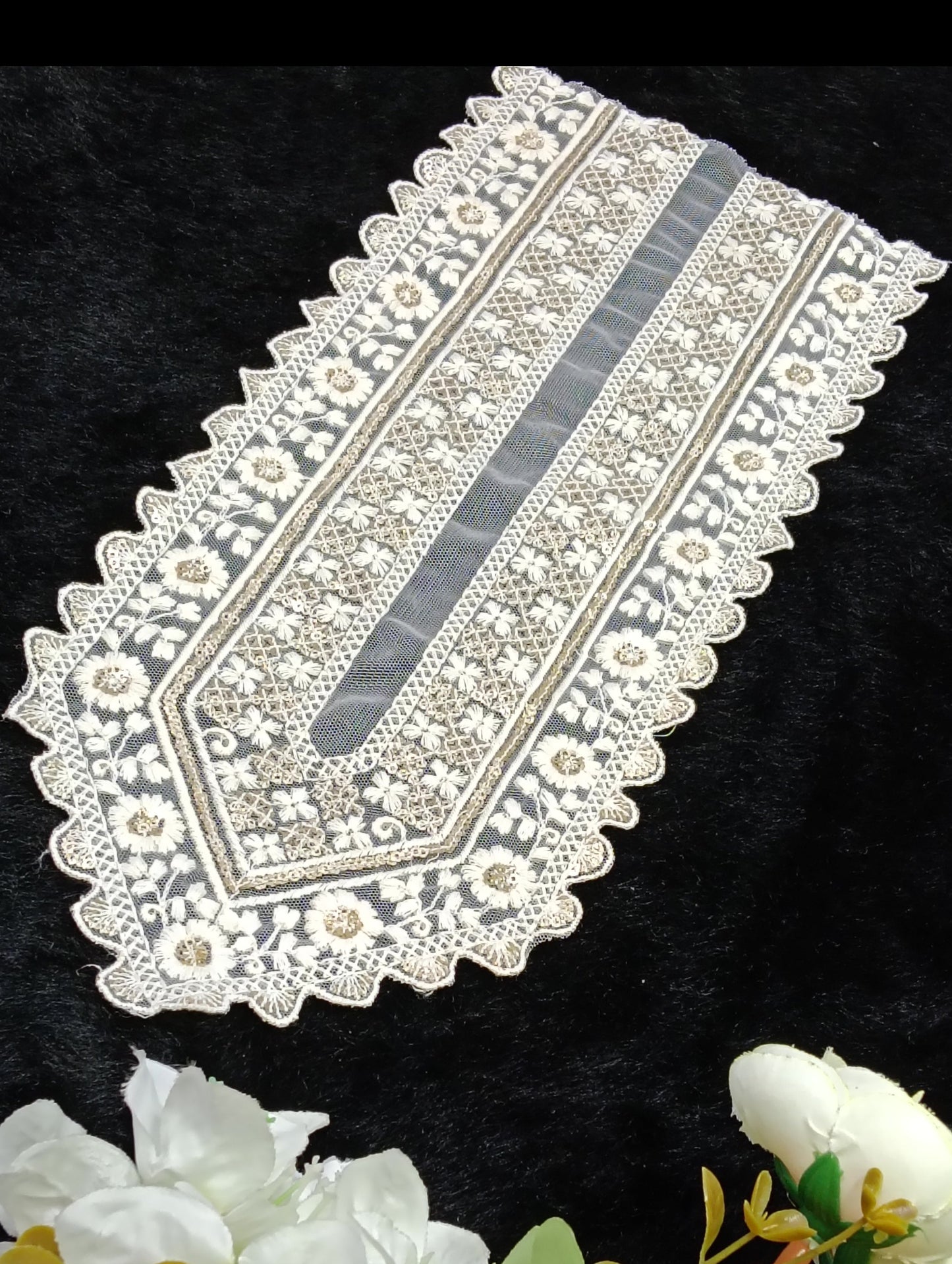 Decorative lace table runner with floral arrangement on a black background